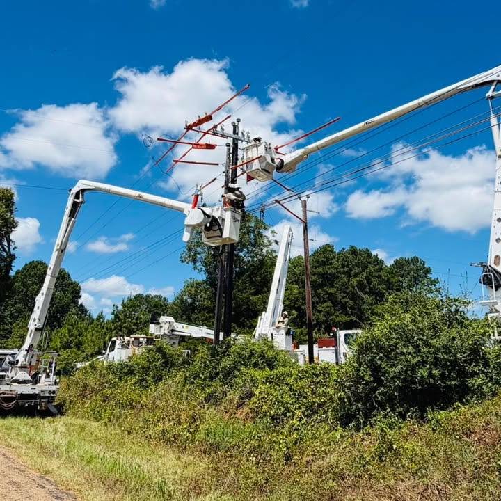 Utility crews working on overhead power lines from bucket trucks